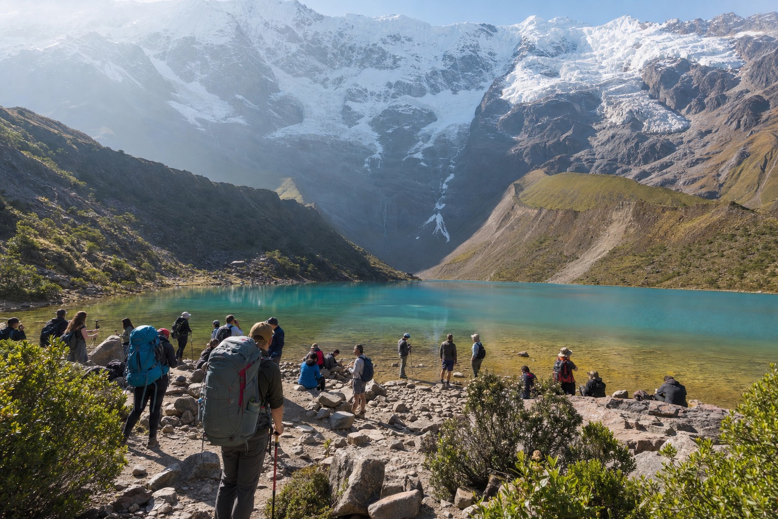 Day hikers and backpack-carrying trekkers mingling on the morning shore of Humantay Lake