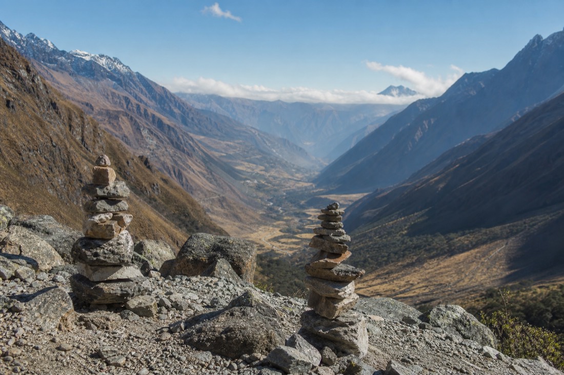 Stone apacheta cairns stacked on the moraine beside Humantay Lake with the valley below