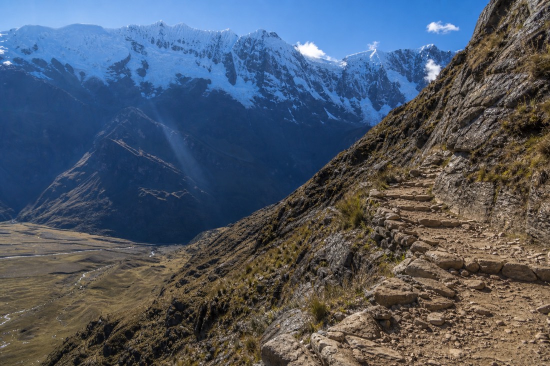Steep rocky switchback trail climbing above the Soraypampa plain toward Humantay Lake under a clear morning sky, no people
